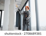 Professional builder applying a paint roller while decorating the interior of a newly constructed apartment, showcasing skill and precision