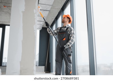Professional builder applying a paint roller while decorating the interior of a newly constructed apartment, showcasing skill and precision