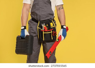 Professional builder with different tools on yellow background, closeup