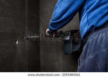 Professional builder drilling wall with hammer drill.