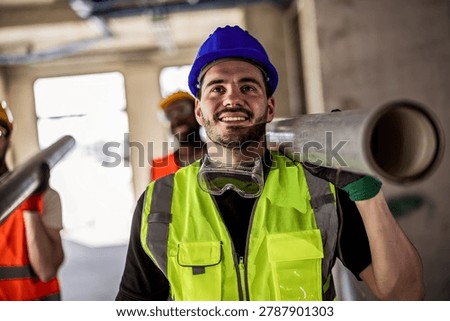 Professional builder holding a heavy pipe on his shoulder while a coworker carries the other end. Fully equipped crew in high-visibility gear on a building site. Ideal for industry.