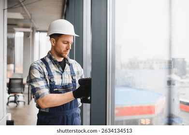 Professional builder using cordless screwdriver, installing window frames in a new office building, ensuring precise and secure placement