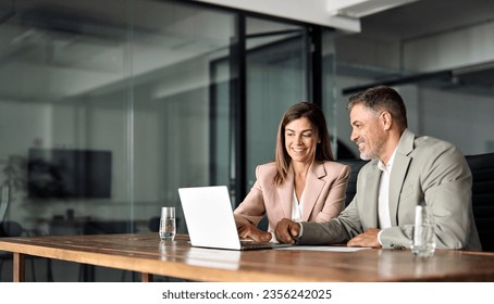 Professional business executive managers office team working using laptop computer sitting at table. Two mid aged colleagues company board discussing digital strategy at corporate meeting. Copy space - Powered by Shutterstock