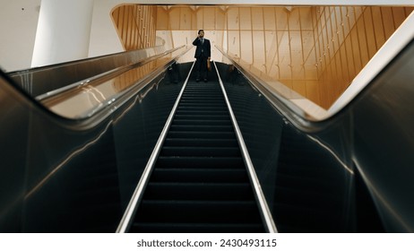 Professional business man using phone calling while using escalator. Skilled caucasian executive manager talking to business team to report and discuss marketing idea or plan. Front view. Exultant. - Powered by Shutterstock