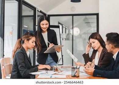 Professional business meeting with diverse team discussing strategies and analyzing data. Engaged individuals collaborate using digital devices and documents. - Powered by Shutterstock