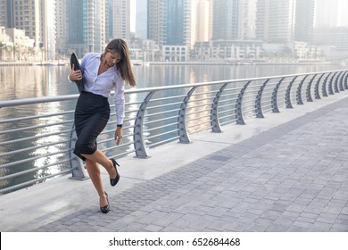 Professional business woman checking her high heels on a boardwalk.