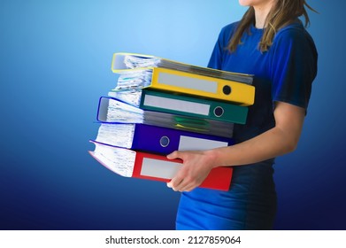 Professional business woman holding folder full of paper documents. Office girl with stack of ring binders for archiving documents over blue isolated background.