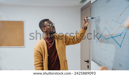 A professional businessman is captured while confidently presenting a growth chart during a business meeting. The interactive session is being recorded, showcasing effective communication skills.