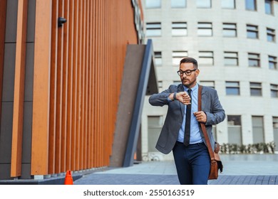 A professional businessman checks his wristwatch while walking in a modern urban setting. Dressed in a suit, he appears focused and engaged, suggesting themes of time management and professional life. - Powered by Shutterstock