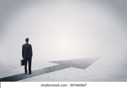 A professional businessman thinking while standing on a black arrow pointing forward in grey space concept