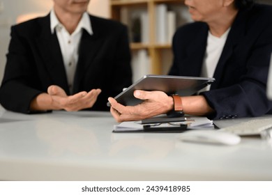 Professional businesspeople analyzing marketing data on digital tablet at office - Powered by Shutterstock