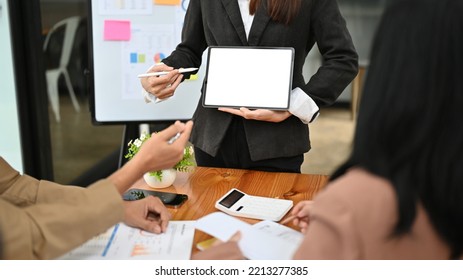 Professional Businesswoman Or Female Boss Training Her Staff In The Meeting, Presenting Or Displaying Something On Tablet Screen, Holding A Tablet White Screen Mockup. Cropped Image