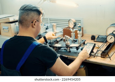 Professional calibration of pressure gauges and sensors. Working man is engaged in verification of control and measuring devices at workplace.. - Powered by Shutterstock