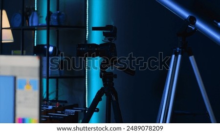 Professional camera equipment in empty blue neon lit creative photography studio. Video production gear in multimedia agency office specialized in post production editing