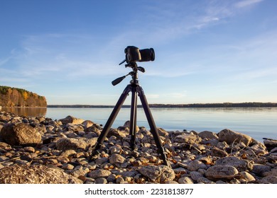 Professional camera on tripod at rocky lakeside