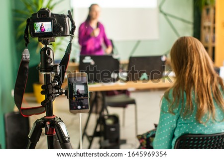 Professional camera is recording seminar with optional accessory. Woman making presentation, lection or meeting.