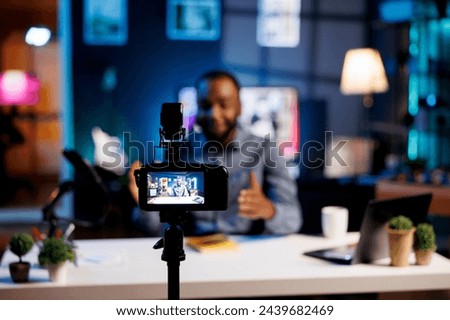 Professional camera used to record tech tutorial on how to repair damaged electronics. Technology guru in blurry background using video production gear to produce content for audience