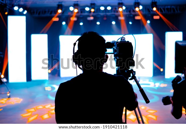 Professional cameraman\
- covering on event with a video, cameraman silhouette on live\
studio news, Selective\
focus