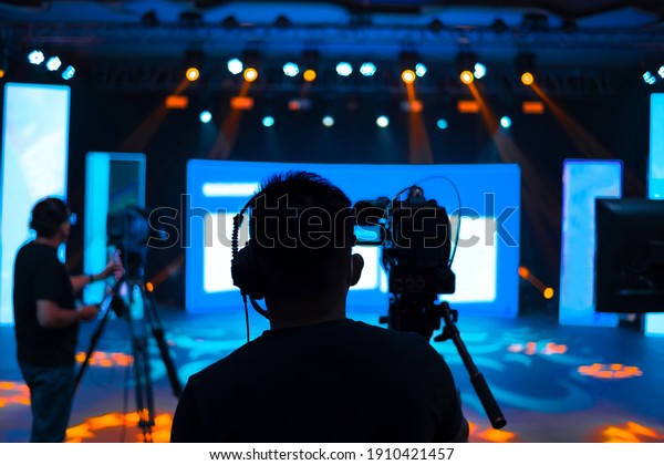 Professional cameraman\
- covering on event with a video, cameraman silhouette on live\
studio news, Selective\
focus