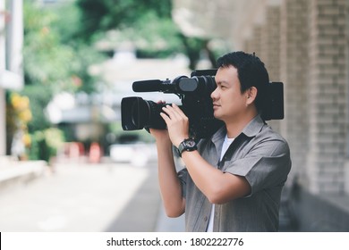 Caméraman professionnel utilisant un caméscope professionnel en plein air sur fond flou.