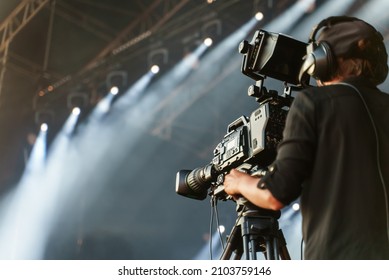Professional camerawoman broadcasting live concert on camcorder.