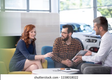 Professional car dealer offering luxurious vehicles during meeting with buyers in salon