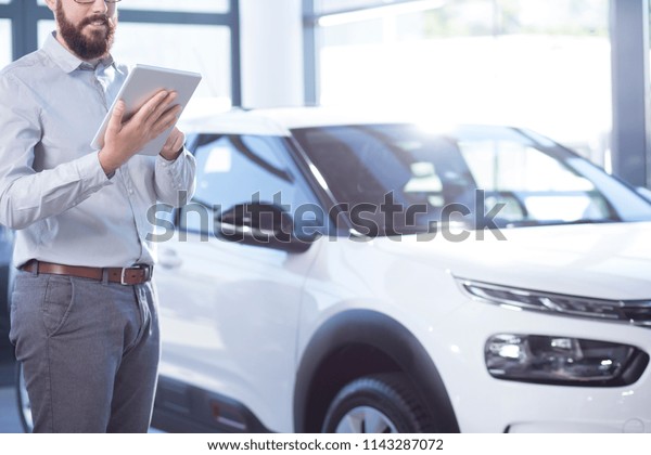 Professional car dealer with tablet in exclusive\
showroom with luxury\
vehicles