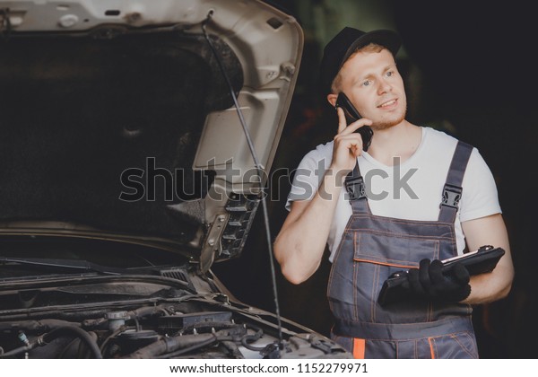 Professional car mechanic Calls on phone to\
client in auto repair\
service.