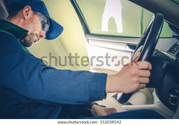 Professional Car\
Mechanic Examining Electronic Systems of the Car While Seating\
Inside. Car Maintenance and\
Inspection.