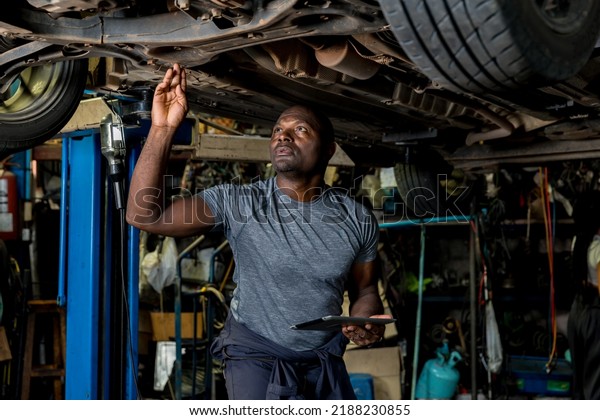 Professional Car Mechanic is Investigating Under a\
Vehicle on a Lift in Service. Auto Service Worker Checking Car\
Under Carriage Look For Issues. Car service technician check and\
repair customer\
car.