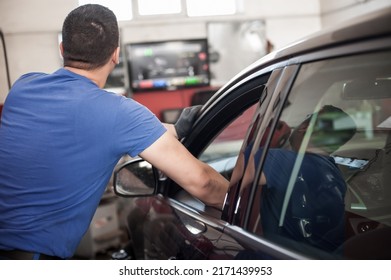 Professional Car Mechanic In Overalls Repairs Car In Garage With Closed Car Door