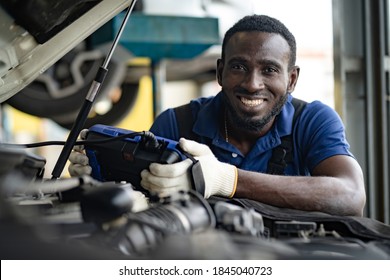 Professional car mechanic repair service and checking car engine by Diagnostics Software computer. Expertise mechanic working in automobile repair garage. 