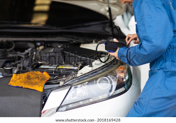 Professional car mechanic\
repair service and checking car engine by Diagnostics Software\
computer. Expertise mechanic senior man working in automobile\
repair garage.