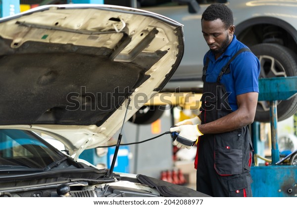 Professional car mechanic repair service and\
checking car engine by Diagnostics Software computer. Expertise\
mechanic working in automobile repair garage.\
