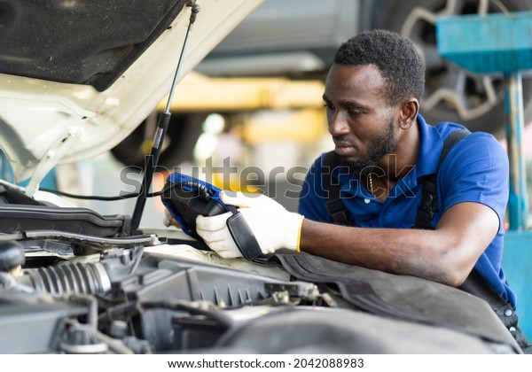 Professional car mechanic repair service and\
checking car engine by Diagnostics Software computer. Expertise\
mechanic working in automobile repair garage.\
