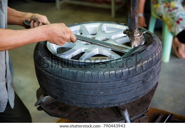 Professional car mechanic replace tire on wheel\
in auto repair service,modern car waiting for the mechanic to\
change its wheels or tires Bearded mechanic changing car\'s tire on\
a tire changing\
machine