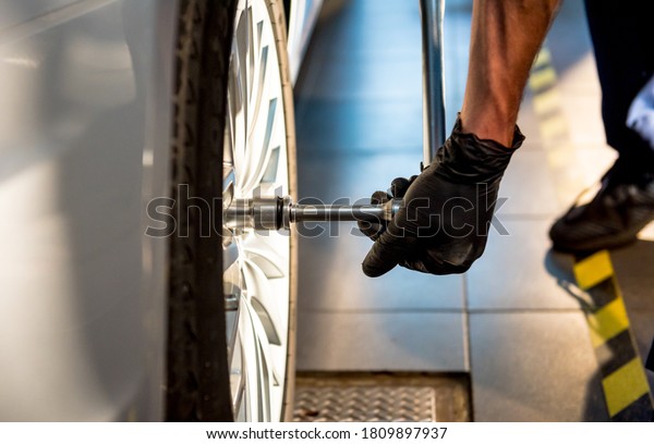 Professional car mechanic working with in auto\
repair service. Repair of\
wheels