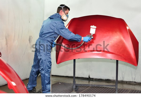 Professional car\
painter, painting red\
bonnet.