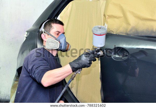 Professional car\
painter working at a black\
vehicle.
