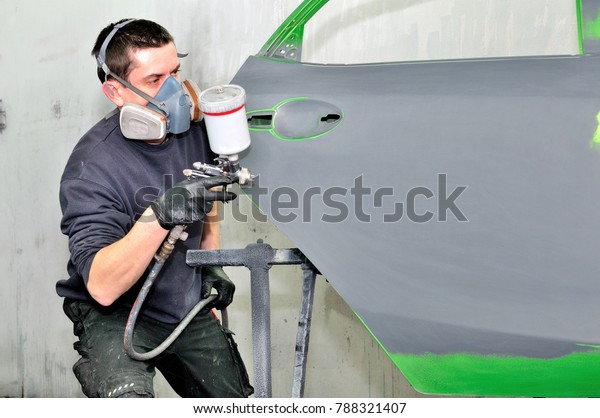 Professional car\
painter working at a green\
door.