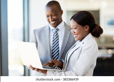 professional car sales consultants working on laptop computer inside vehicle showroom - Shutterstock ID 383386939