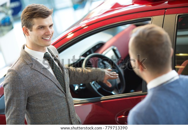 Professional car salesman working with his\
customer showing new automobile describing benefits of the vehicle\
positivity confidence friendly helpful service rental advise people\
sales retailer