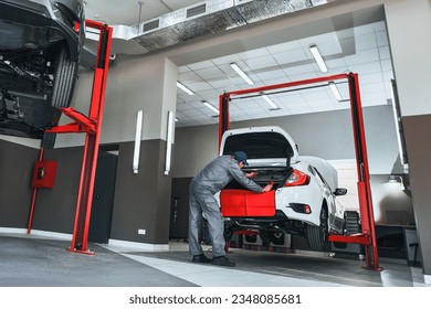 Professional car service. Comprehensive Car Care. Panoramic View of Dealership Service with Mechanic Repairing a Modern Sedan Car. Car shop.