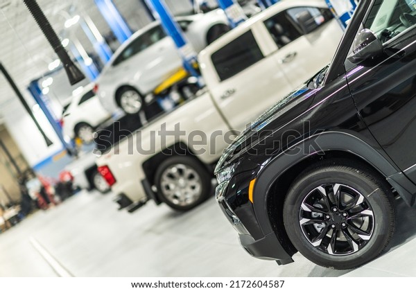 Professional Car Service and Detailing\
Facility Interior View. Cars Parked in a Line in a Queue for\
Maintenance and Repair Work. Work organization of a big\
workshop.