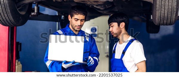 Professional\
car technician mechanic team in uniform use laptop work fixing\
vehicle car engine and maintenance repairing checking under the car\
in auto service. Automobile service\
garage