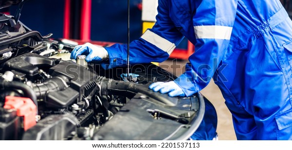 Professional car\
technician mechanic team in uniform work fixing vehicle car engine\
and maintenance repairing checking under the car hood in auto\
service. Automobile service\
garage
