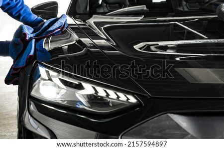 Professional Car Wash and Detailing Worker Cleaning Car Body with a a Soft Cloth. Automotive Industry Theme.