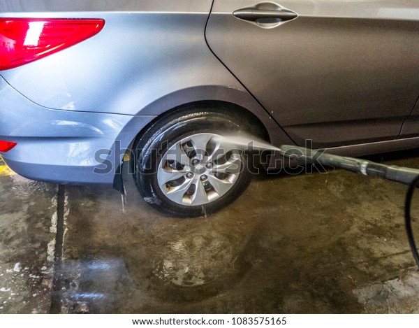 a professional car washer is cleaning the car at car\
wash shop