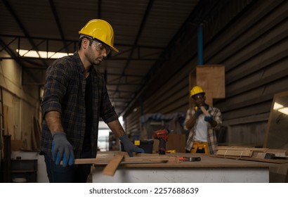 Professional carpenter craftsmen wear safety gear.  He was assembling woodwork on a table for crafts with blur black colleague background. in Carpenter and wood craftsmanship concept - Powered by Shutterstock