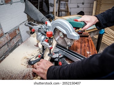 Professional carpenter cutting wooden plank using sliding compound mitre saw